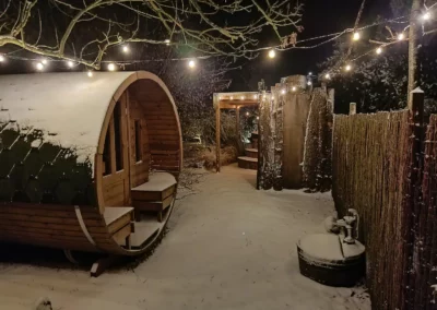 Le spa du gîte Champs des Amours sous la neige avec des guirlandes de Noël