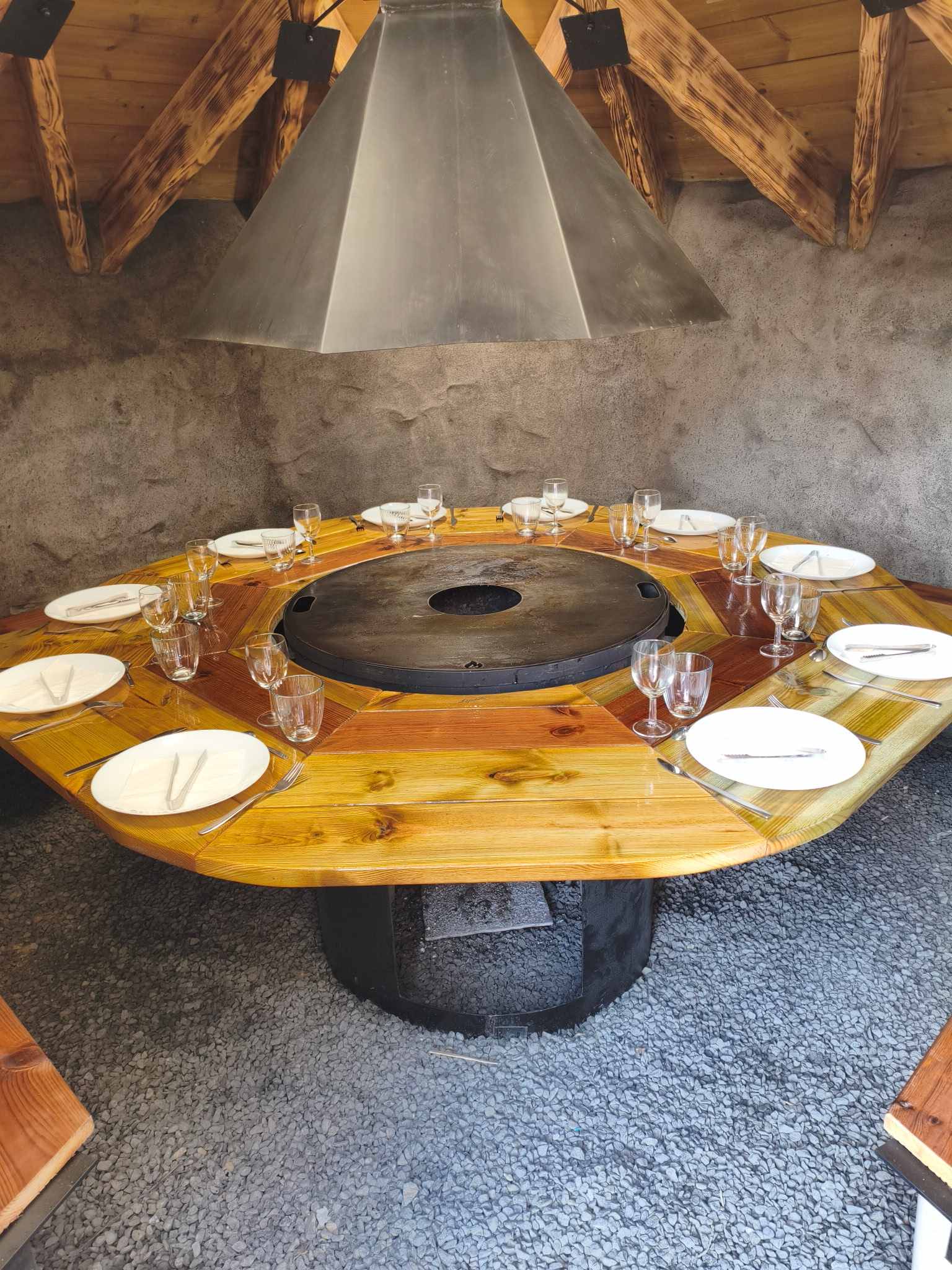Intérieur d'un kota grill : table circulaire en bois dans le Pas-de-Calais pour un repas convivial en groupe